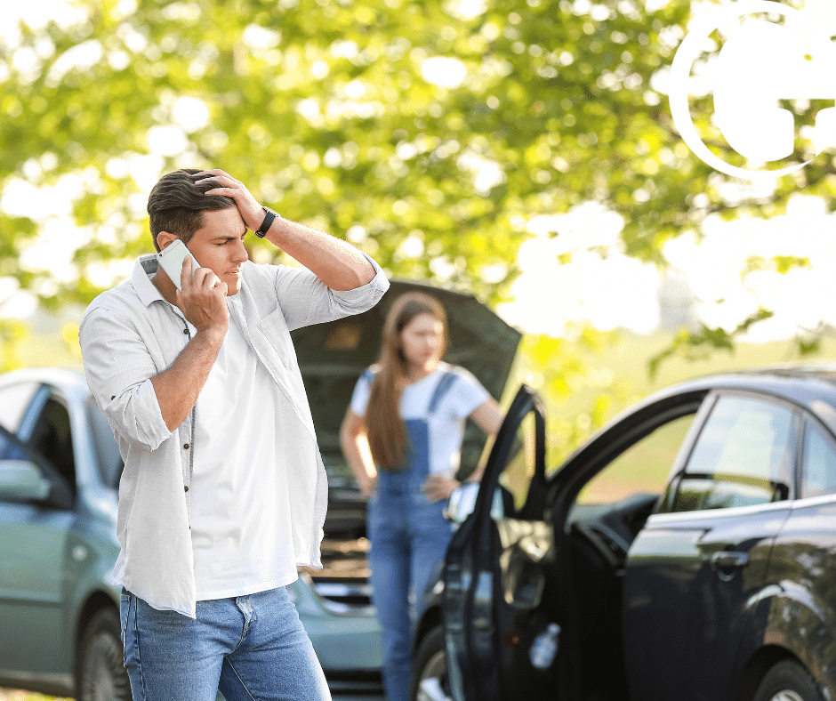 Two people involved in a car accident inspecting their car