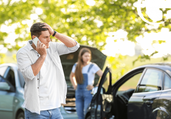 Two people involved in a car accident inspecting their car